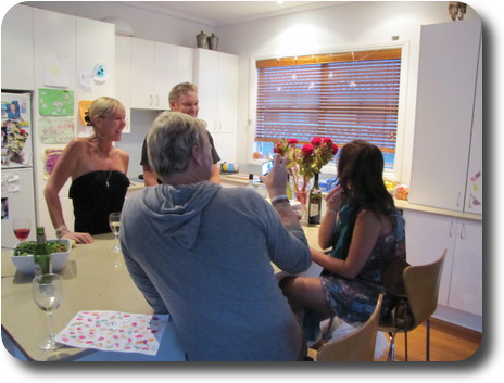 Kitchen island, with man and woman seated near camera, man and woman standing on far side