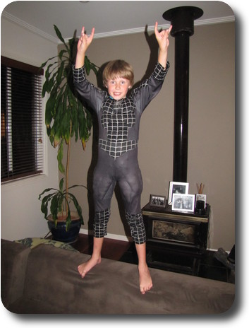 Little boy in Spiderman suit jumping with arms raised