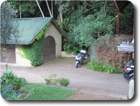 Motorcycle parked next to concrete tank, adjacent to garage style building