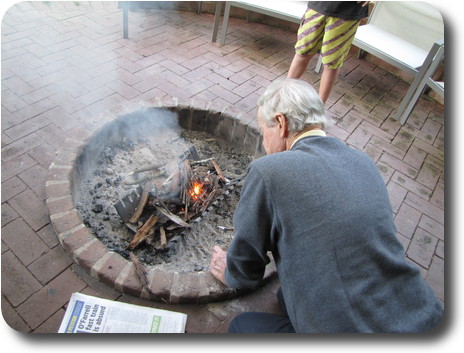 Man kneeling at fire pit starting a fire