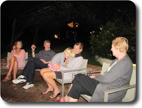 Four adults and a little girl in chairs around the fire pit.