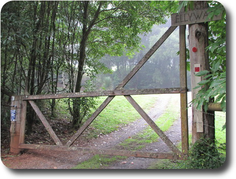 Wooden gate hinged on a pole with a name chiselled into a piece of wood