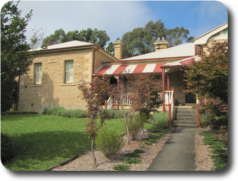 Sandstone building, white iron roof with red/white roof over verandah