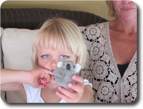 Little girl holding a tiny koala toy, and her mum next to her