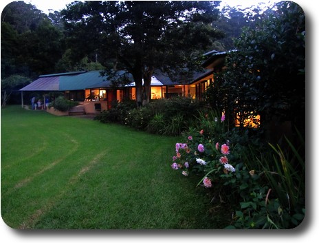 Lawn on the left, garden and house on the right; people gathered at far end