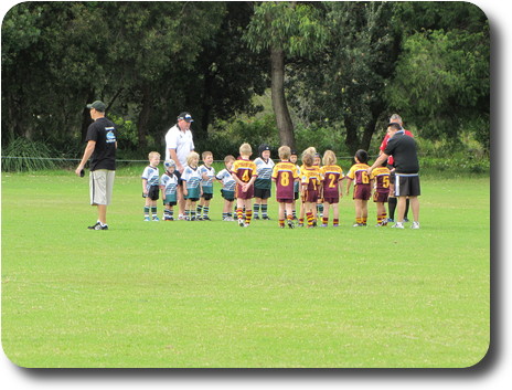 Two teams of littlies, a couple of coaches and a referee on the field