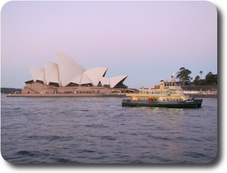 Smaller Sydney ferry passing the Opera House, with pink tones in the eastern sky