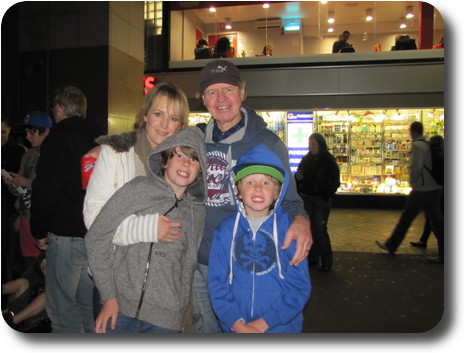 One man, one woman and two boys in front of shops