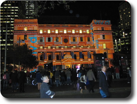 Sandstone building with orange illumination, covered in writing with dark sky