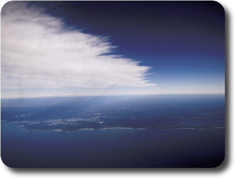 Ragged edge of cloud in sky, with coastal hills and waterways behind