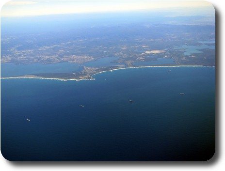 Coal ships waiting to enter port, with sandy coastline and some lakes inland