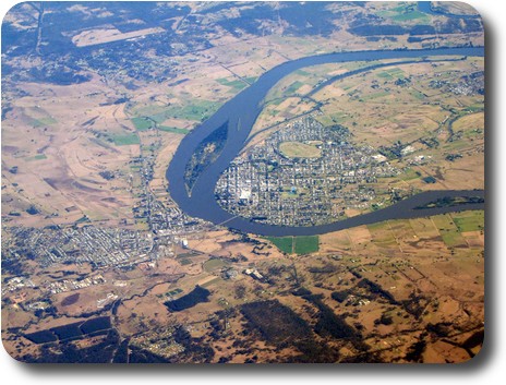 U shaped river bend, with towns on both sides and connecting bridge; several islands in the river