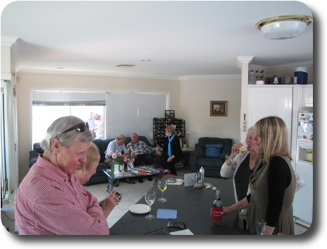 View from kitchen into family room: people standing in kitchen, some seated in family room