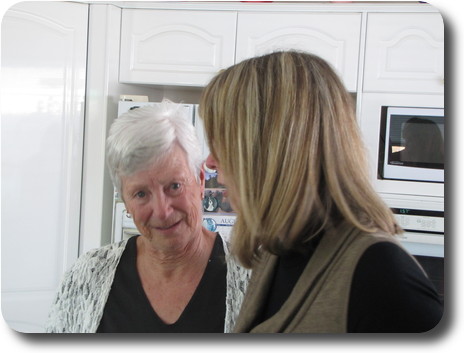 Two women in kitchen, one looking into camera, the other looking sideways