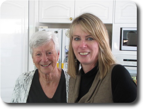 Two women in kitchen, both looking at the camera