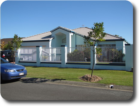 Light cyan coloured home, single level, grey tile roof and white fence