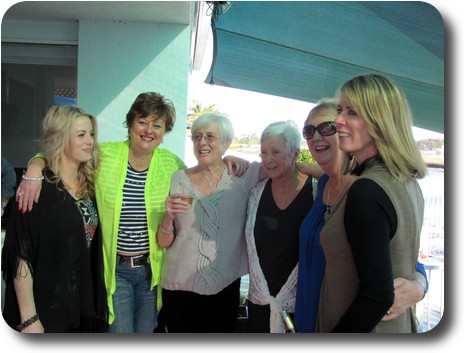 6 women standing in a semi-circle with arms on shoulders