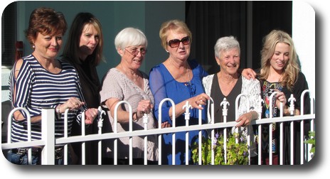 6 women standing alongside each other, behind a swimming pool fence