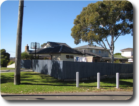 Grey fence with clothes line and carport behind it