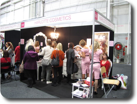 Display booth with pink dressed ladies promoting the brand to a number of enquirers