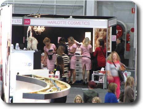 Booth with ladies in pink dresses promoting lipstick etc.