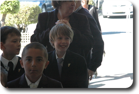 Smiling boy at end of line, with teacher behind