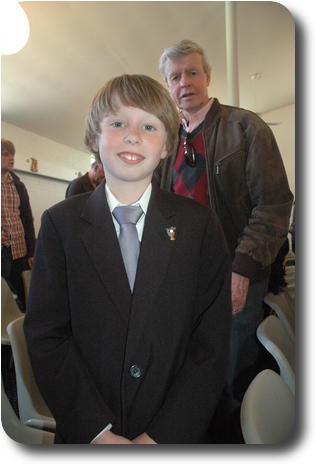 Little boy with man behind; still in row of seats in church