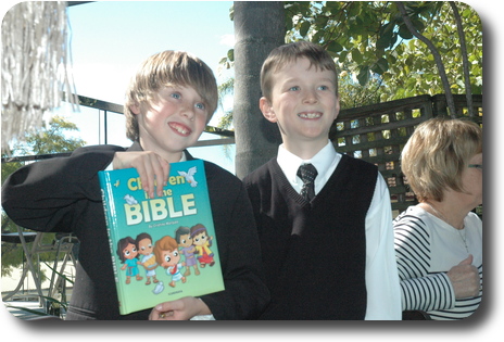 Two little boys in formal attire, one of them holding a book