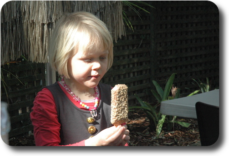 Little girl holding an ice cream bar, covered in chocolate and nuts