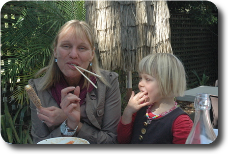 Woman with 2 straws in her mouth, and her daughter standing next to her