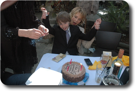 Little boy in suit, sitting on mother's lap, both holding their arms in the air