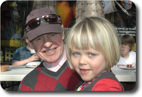 Man wearing cap, with little girl on his knee