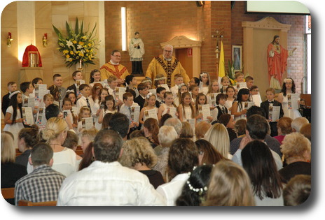 Youngsters standing at front of altar having received their certificate