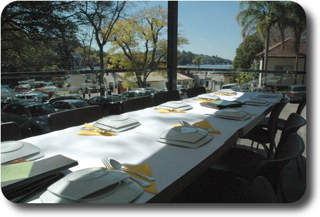 Long table with upturned plates, partly in shade, with view over the river