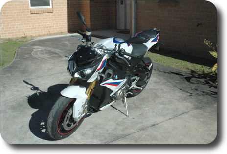 Left front side view of white, blue red motorcycle, black frame