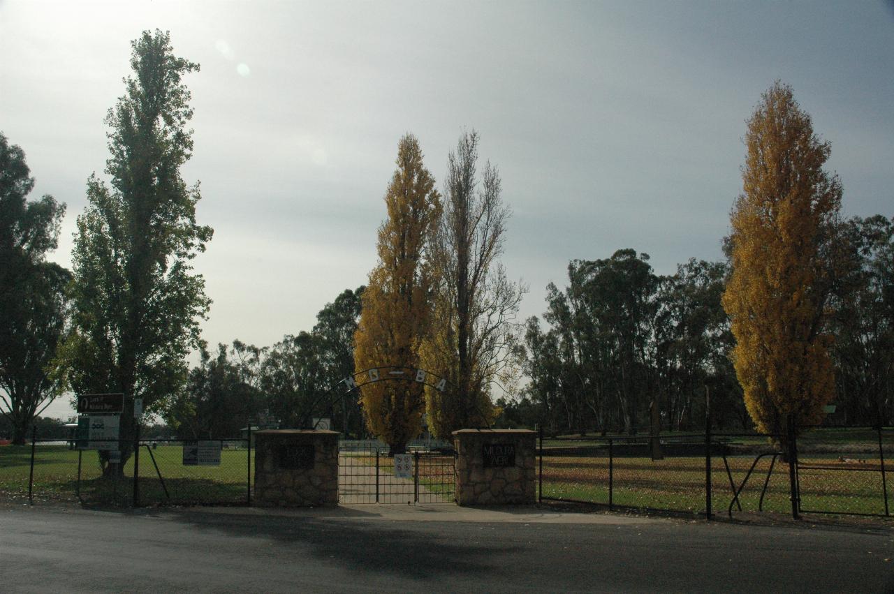 Small stone pillars with metal gate leading to park area with yellow poplar trees