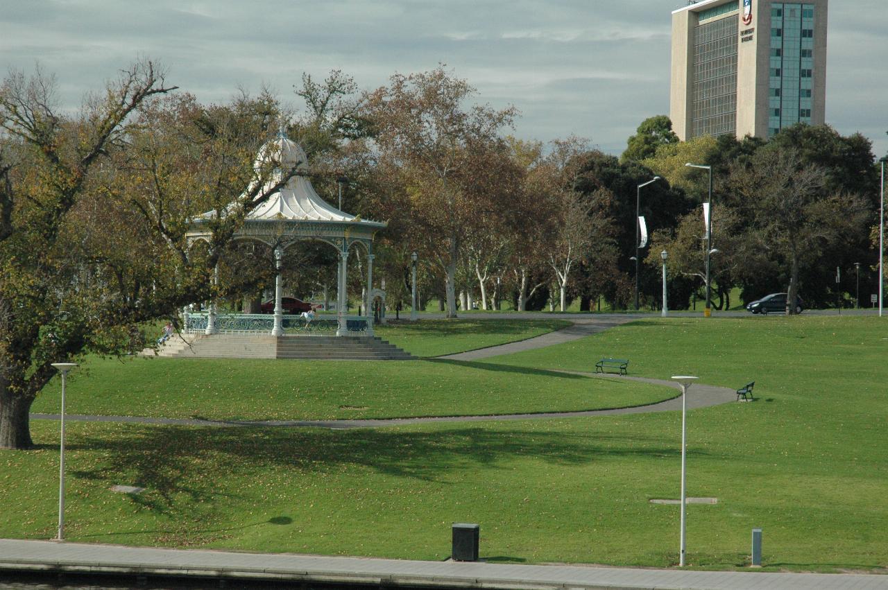 Grassy hill, white rotunda to trees along road and another park behind