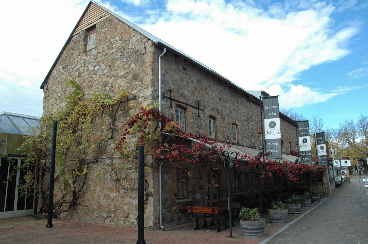Long two storey + attic stone building, with front awning and vines growing over it and building side