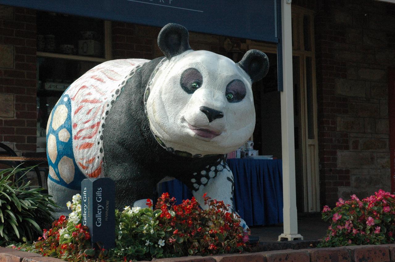 Large panda statue, colorfully decorated, in garden