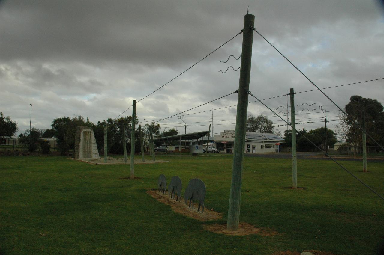 Grassy area with green wooden poles and wires strung along them, not electrical wires