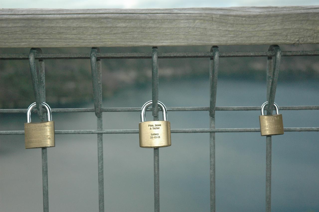 Close up of metal mesh fence, with small engraved padlocks attached
