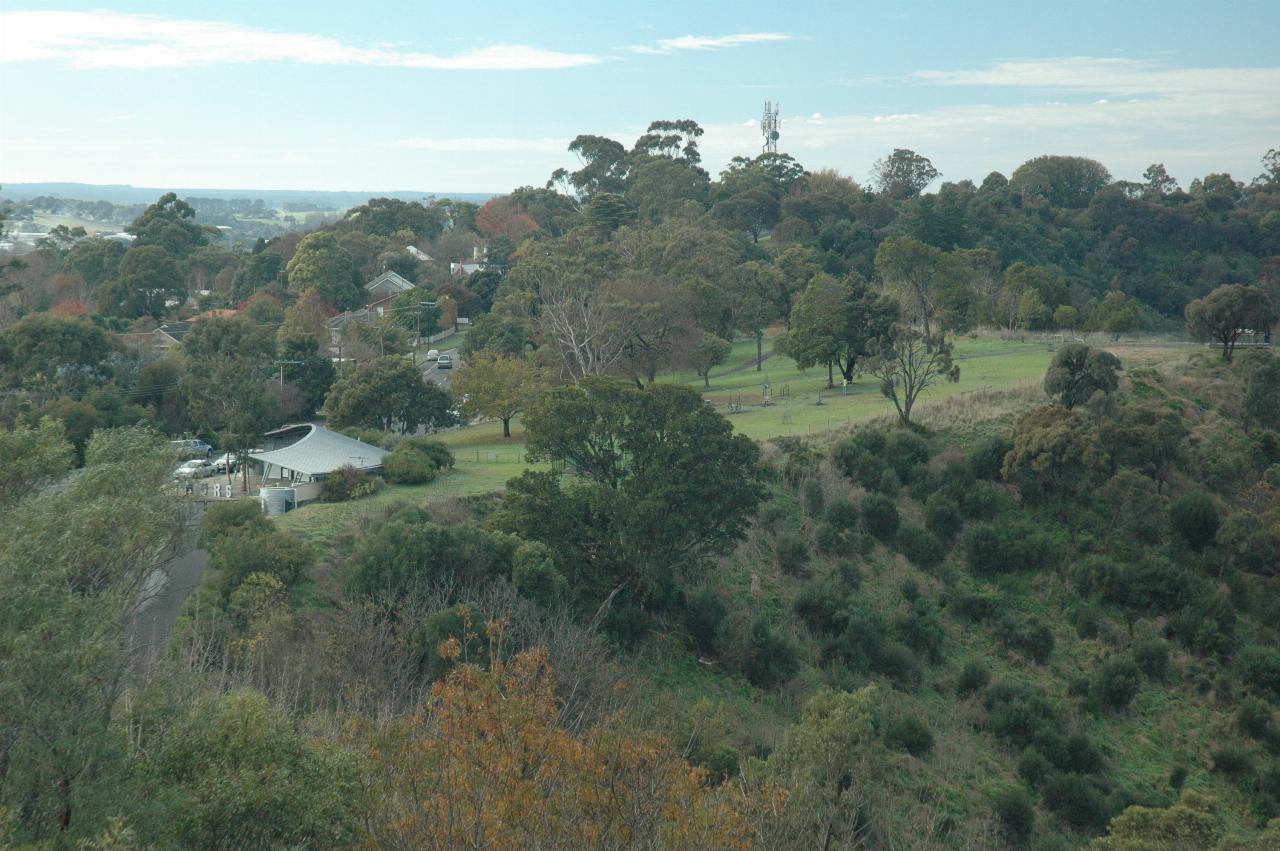 Park area with trees and semi-circular building, and distant views of other buildings