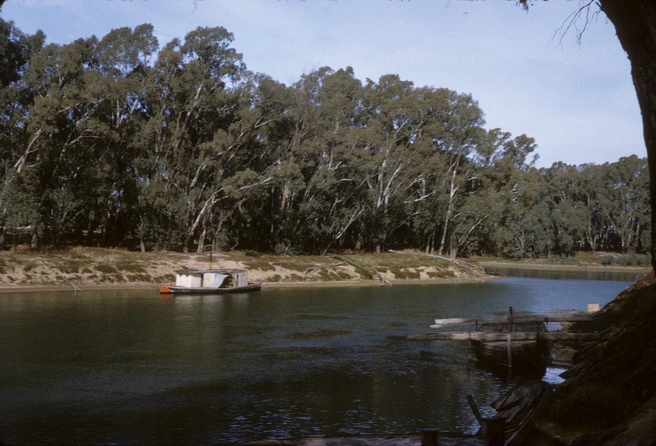 River bend with an anchored paddle wheeler near tree lined bank