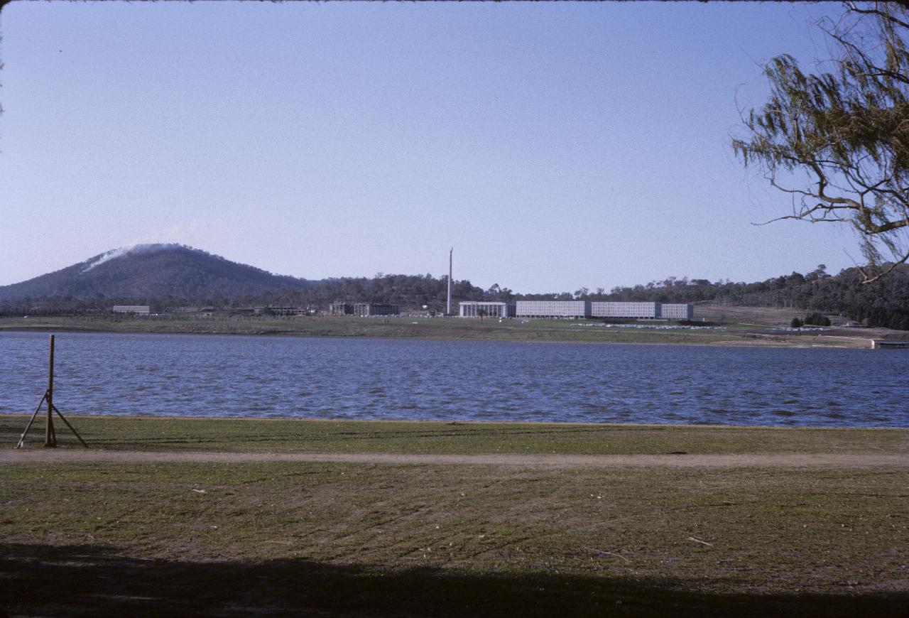 Lake. mountain with smoke rising, obelisk and office buildings