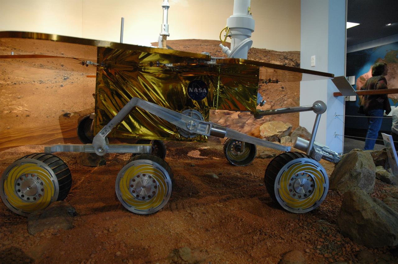 Mars rover in display of simulated surface of Mars; side on view