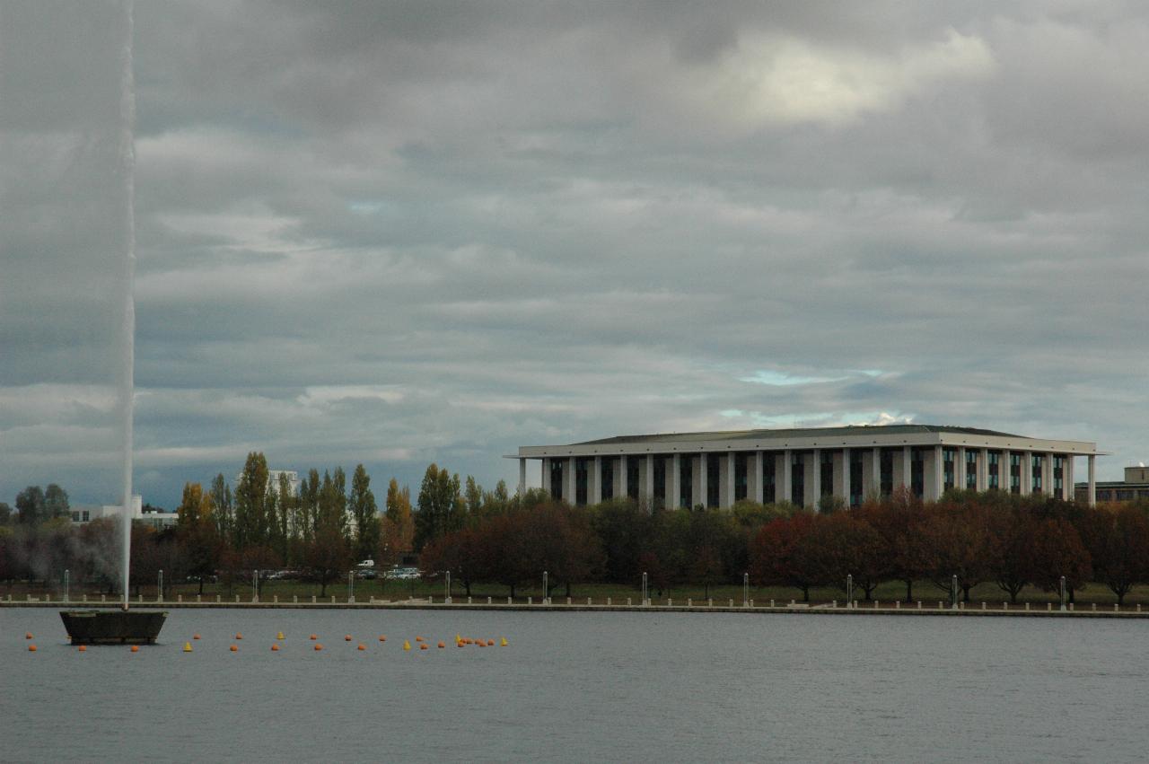 Water jet, and classical building with columns across lake