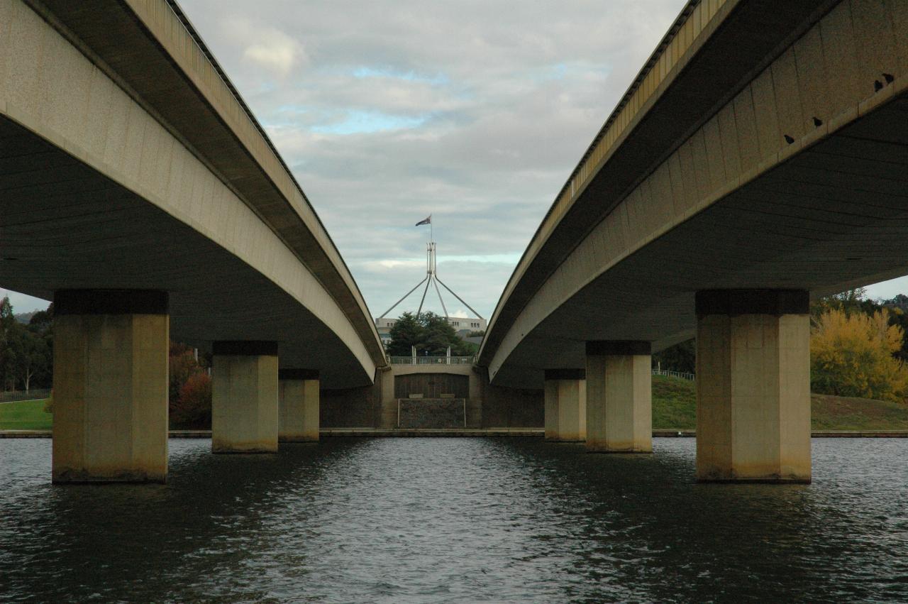 Giant flagpole visible between twin bridges over lake